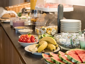 A buffet with various food items including tomatoes, bananas, watermelon, and dairy products.