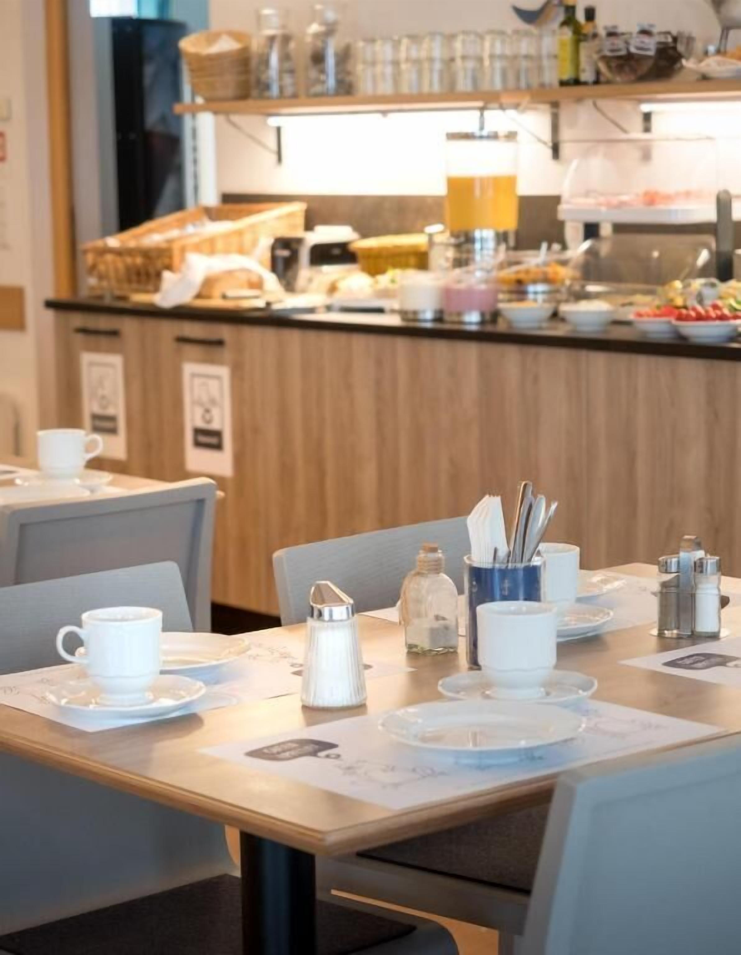 Un ambiente para el desayuno con un bufé de fondo, una estación de café y un comedor moderno y limpio.