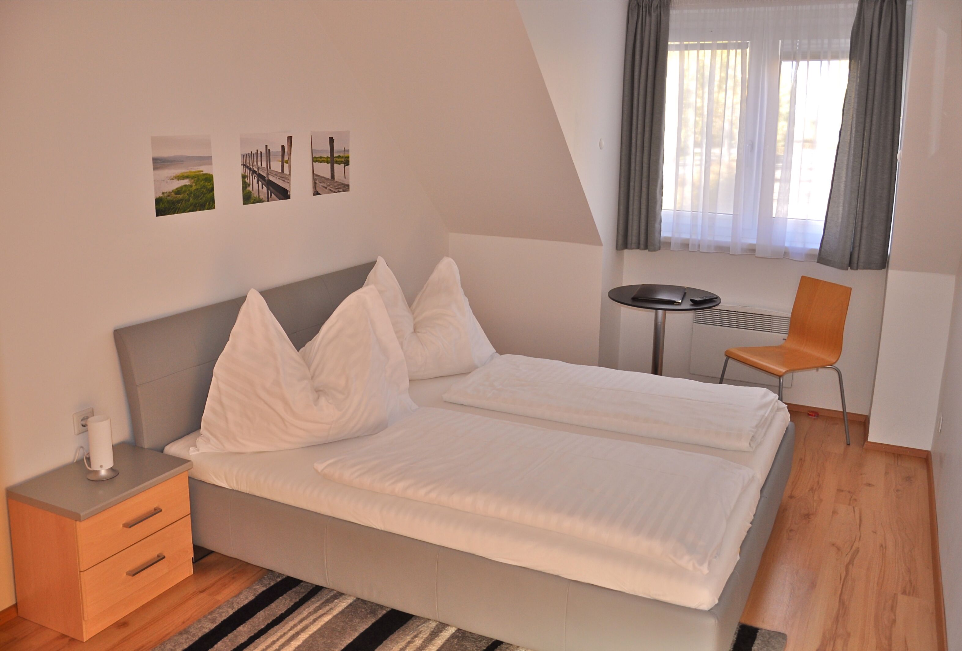 A bedroom with a bed, a nightstand, a chair, and a small table.