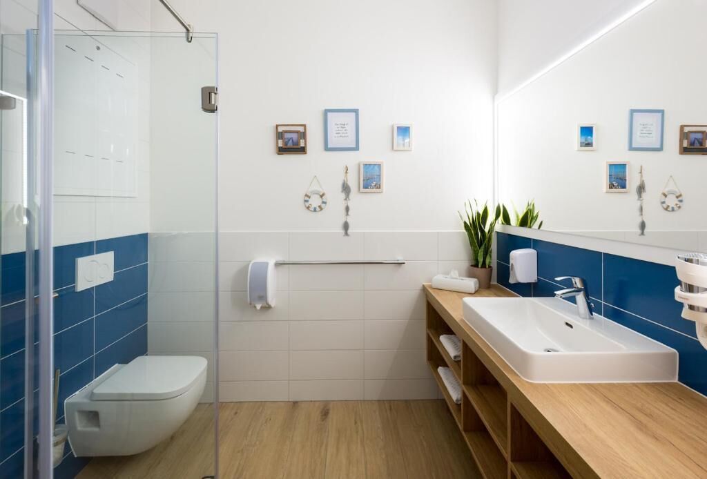 Un bagno moderno con box doccia in vetro, un WC bianco, un mobile bagno in legno con lavello e uno specchio.