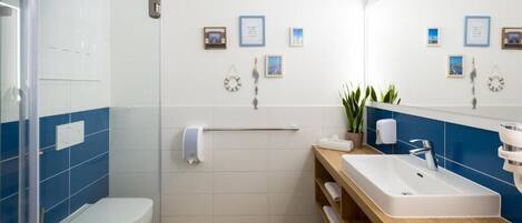 Un bagno moderno con box doccia in vetro, un WC bianco, un mobile bagno in legno con lavello e uno specchio.