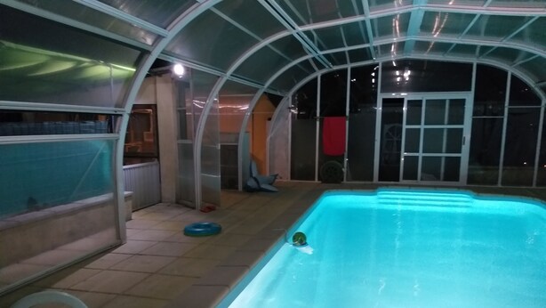 Ein Hallenbad mit Glasdach, einer Leiter und einem roten Stuhl.
