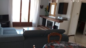 Ein Wohnzimmer mit einer Couch, einem Fernseher, einem Kamin und einem Essbereich mit Tisch und Stühlen.