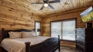 Una camera da letto con pannelli in legno, un letto, una cassettiera e una ventola a soffitto.