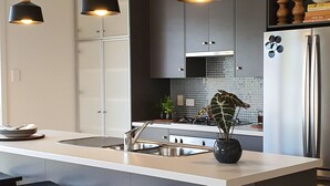 A modern kitchen with a central island, bar stools, pendant lighting, and a stainless steel refrigerator. - Luxury beach stay,  close to the famous SA wine regions (Aldinga)