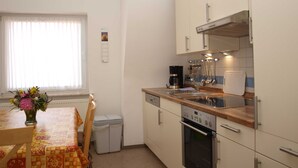 Cocina compacta con comedor, que incluye cafetera, horno y electrodomésticos de acero inoxidable.