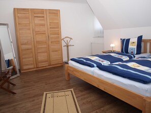 Une chambre à coucher avec un lit en bois, une armoire, une lampe sur pied et une table de chevet avec une lampe.