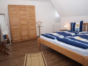 Ein Schlafzimmer mit einem hölzernen Bett, einem Kleiderschrank, einer Stehlampe und einem Nachttisch mit Lampe.