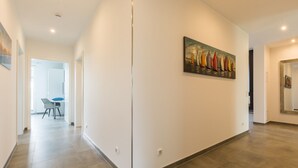 Um corredor com decoração moderna, uma sala de jantar com mesa e cadeiras, e um quadro na parede.