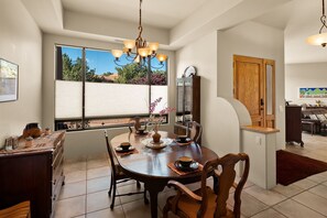 Enjoy meals in this dining area with a round table for four, a chandelier, and a large window offering a view of the outdoors.