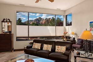 Enjoy a scenic view of the surrounding mountains and greenery from the large window in this stylish living room.