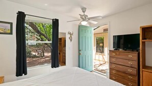 A bedroom with a bed, a ceiling fan, a TV, a dresser, and a door leading to an outdoor area. - Ranch Style Home Uptown Sedona, View/BBQ/Patio! (Sedona)