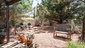 An outdoor patio area with wooden benches, potted cacti, and a pergola structure. - Ranch Style Home Uptown Sedona, View/BBQ/Patio! (Sedona)