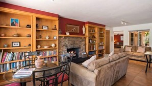 A living room with a fireplace, bookshelves, a sofa, and a dining area. - Ranch Style Home Uptown Sedona, View/BBQ/Patio! (Sedona)