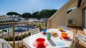 A balcony with a table set for breakfast, overlooking a marina and a pool. - Le Grand Galion by Interhome (Port Camargue)