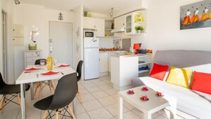 A compact living space with a dining area, kitchenette, and a sofa with colorful cushions. - Le Grand Galion by Interhome (Port Camargue)