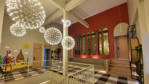 Un interior moderno con suelo a cuadros, una escalera y una pared con espejos y un mural infantil.