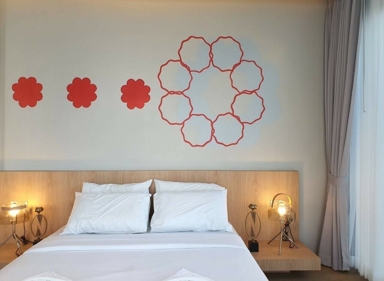 Una camera d'albergo con un letto, due comodini e un elemento decorativo a parete.