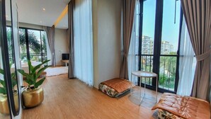 Una habitación amplia con ventanas grandes, una cama, una mesita y un sofá.