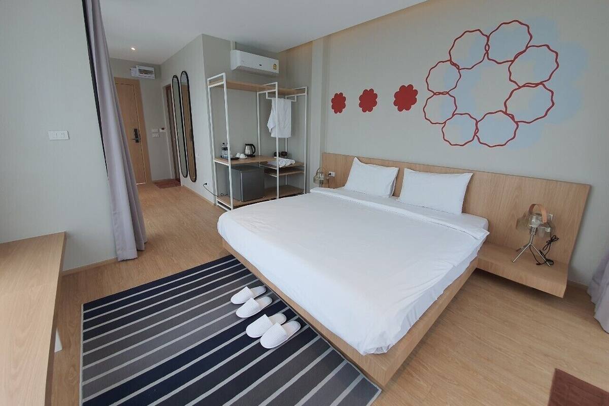 Una habitación de hotel moderna con una cama grande, un escritorio y un armario.