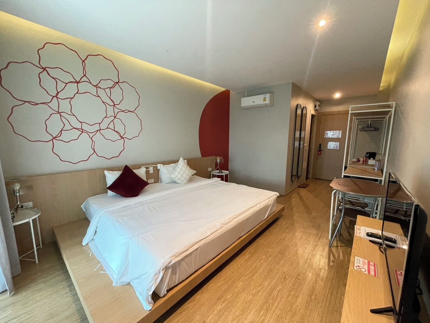 A hotel room with a large bed, bedside tables, a desk, and a mirror.