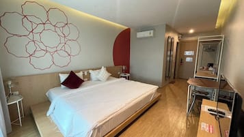 A hotel room with a large bed, bedside tables, a desk, and a mirror.