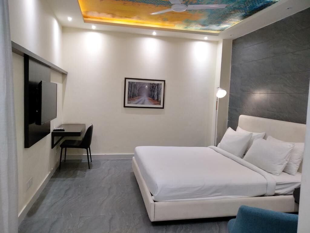 A modern hotel room with a bed, a desk, and a chair.