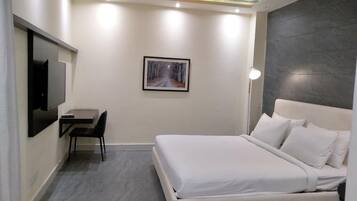 A modern hotel room with a bed, a desk, and a chair.