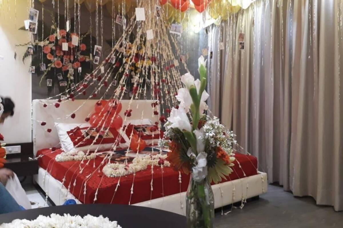 A room with a bed, a vase with flowers, and a curtain.