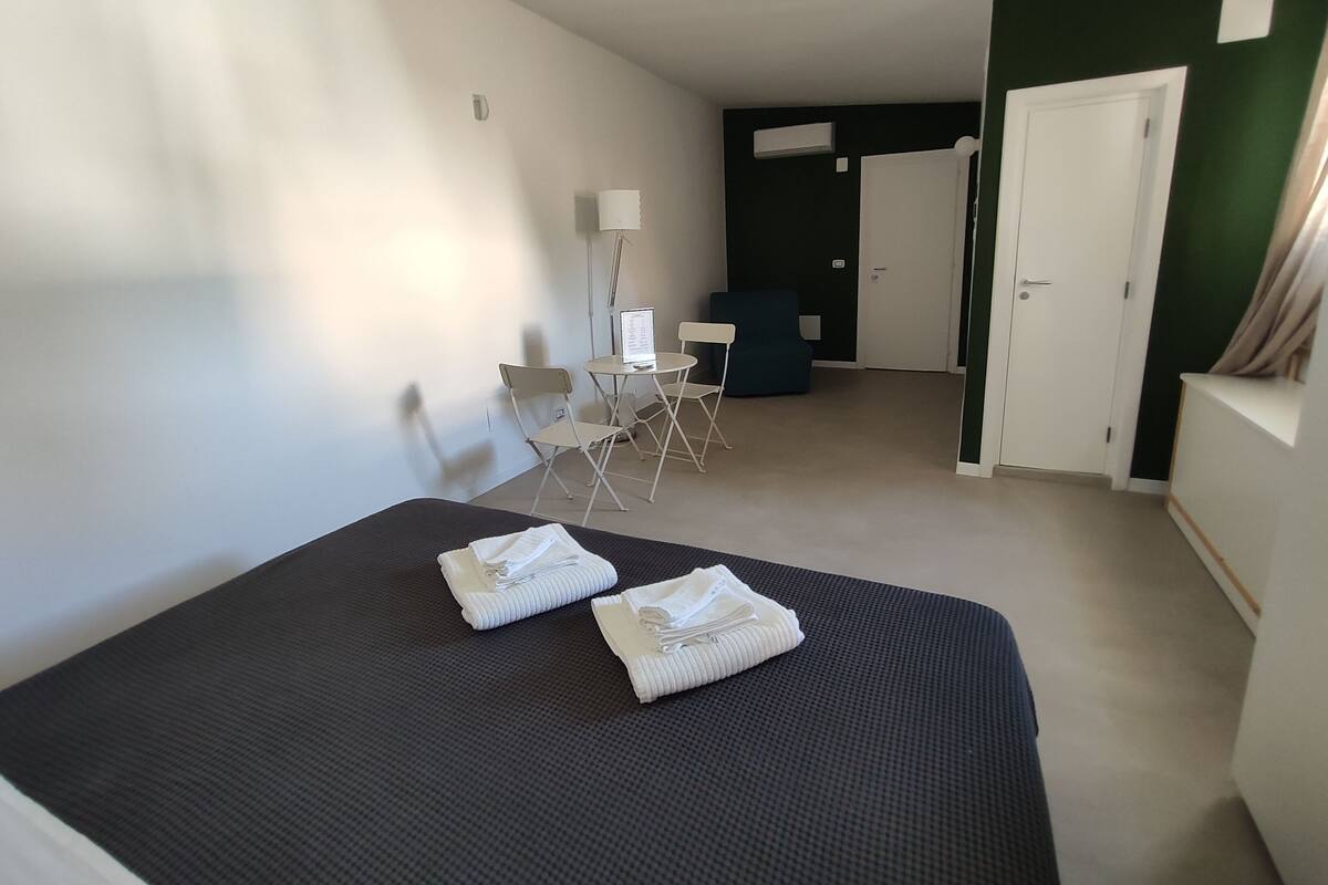 Une chambre d’hôtel avec un lit, un bureau, une chaise et une armoire.