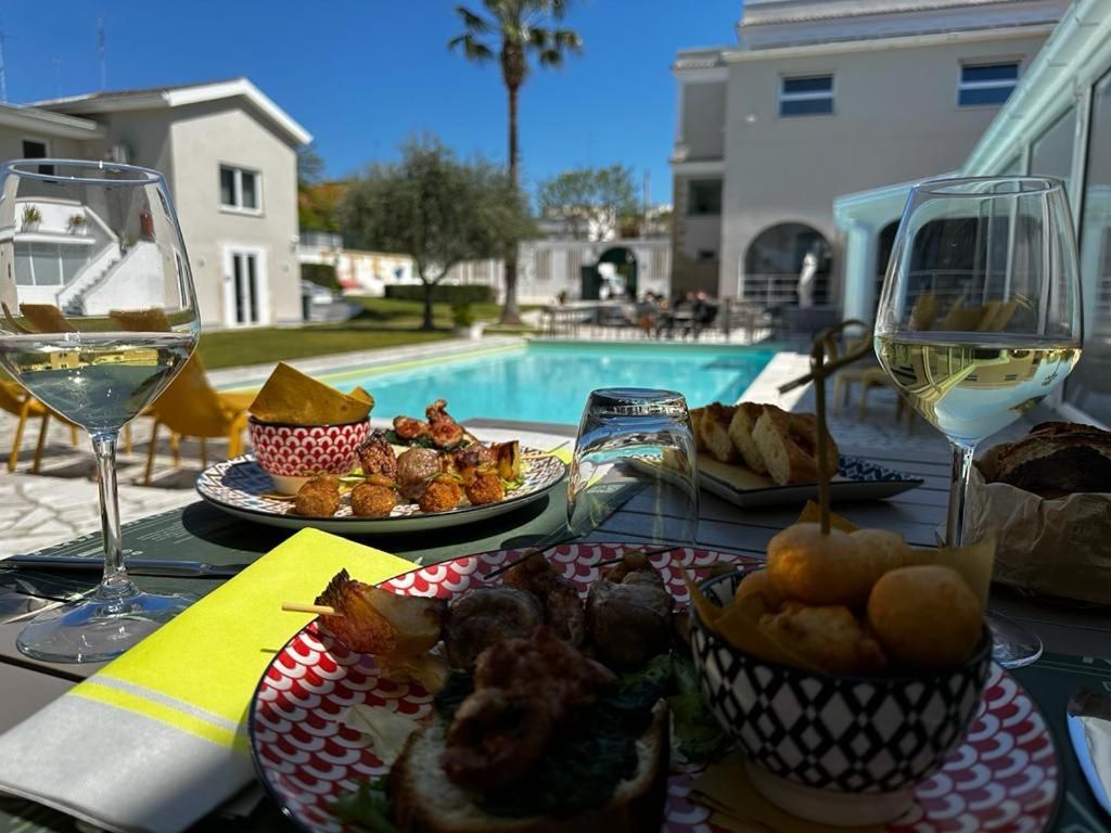 A dining table with food and drinks, a pool in the background, and a building.