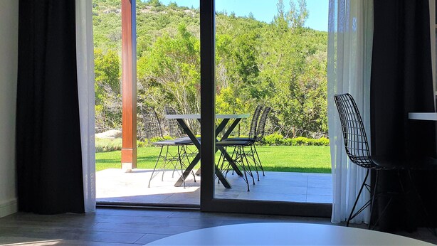 Une pièce dotée d’une porte-fenêtre coulissante donnant sur une terrasse extérieure avec une table et des chaises.