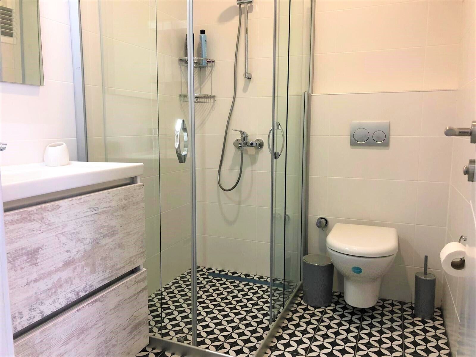 A bathroom with a glass-enclosed shower, a toilet, and a sink with a marble countertop.