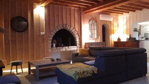 Un salón acogedor con chimenea de piedra, paredes de madera, un sofá, una mesa de centro y un comedor con sillas.