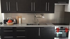 Eine moderne Küche mit dunklen Schränken, einer Edelstahlspüle und einem Backofen.