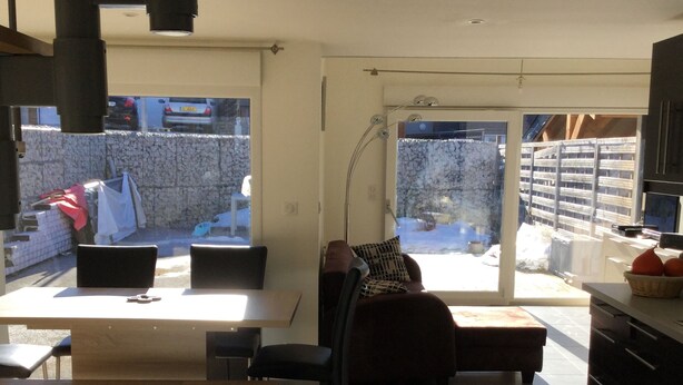 Ein modernes Wohnzimmer mit Essbereich, großen Fenstern und Außenblick.