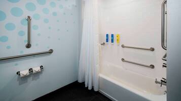 Une salle de bain équipée d’une baignoire, de barres d’appui, d’un porte-rouleau de papier toilette et d’un rideau de douche.