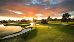 A golf course with a water hazard, trees, and a sunset sky. - Tru By Hilton Goodyear Phoenix West, AZ (Goodyear)