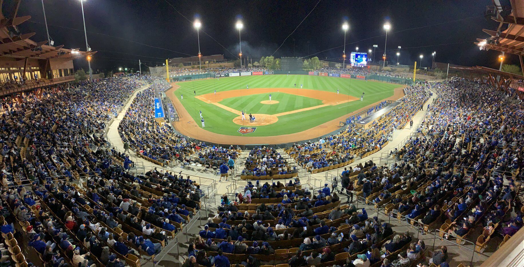 A large stadium with multiple levels of seating, a baseball diamond, and a scoreboard.