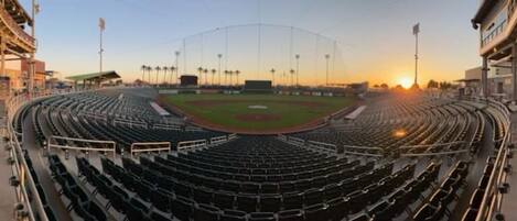 A baseball stadium with multiple tiers of seating, a central field, and a clear sky.