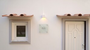 A white exterior wall with a window and a door, each with a small plaque. - House near the sea with Jacuzzi pool, terrace - solarium and garden (META)