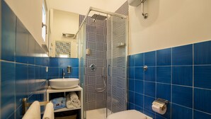 A bathroom with a shower, sink, toilet, and a patterned wall. - House near the sea with Jacuzzi pool, terrace - solarium and garden (META)