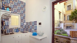 A compact kitchen with a patterned backsplash, a sink, and a window. - House near the sea with Jacuzzi pool, terrace - solarium and garden (META)