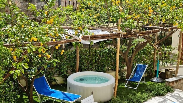 A garden with a hot tub, blue lounge chairs, and lemon trees. - House near the sea with Jacuzzi pool, terrace - solarium and garden (META)