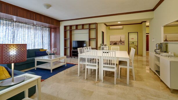 Un amplio salón con una mesa de comedor y sillas, un sofá y un televisor al fondo.