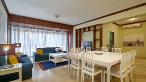 Una sala de estar con sofá, mesa de centro y mesa de comedor con sillas.