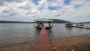 A dock leading to a covered pavilion by a lake with boats docked nearby.