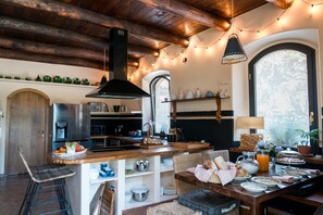A kitchen with a central island, wooden beams, and string lights. - Collina Blu - Villa with gardens and panoramic heated pool (Orvieto)