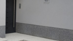 A building entrance with a black door, a nameplate reading "Apartma Borjana," and a wall-mounted light fixture. - Hiša Kramer - Apartment Borjana (Kobarid)