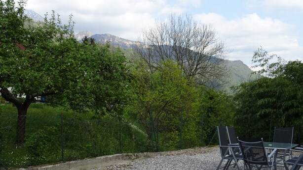 A gravel patio with outdoor seating and a view of mountains. - Hiša Kramer - Apartment Borjana (Kobarid)